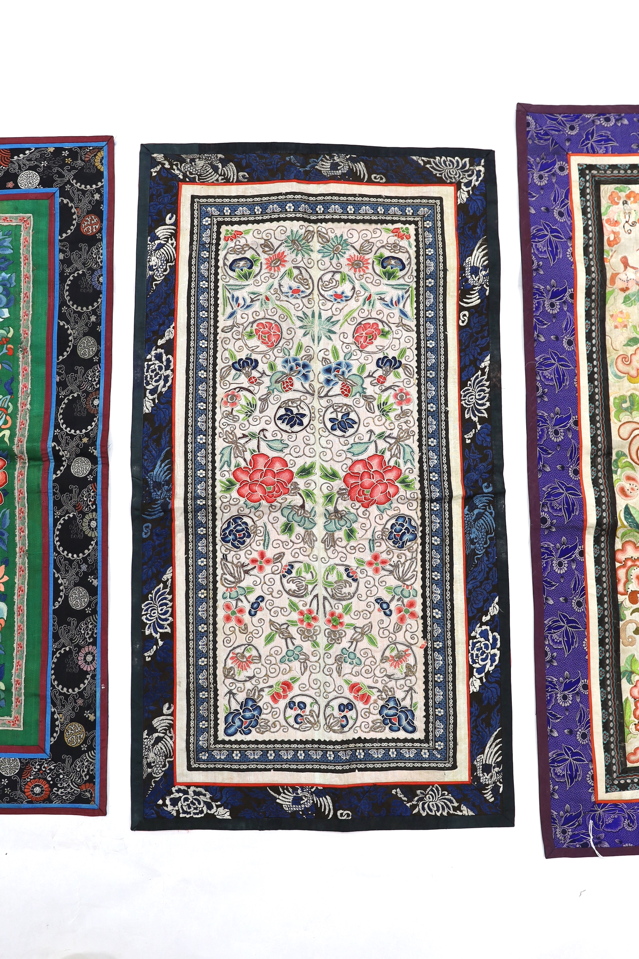 Three Beijing knot pairs of sleeve bands bordered with silk brocade and one pair embroidered with polychrome silks and gold thread longest, 73cm x 32cm including damask border